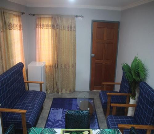 a living room with two blue chairs and a glass table at Mount Olivet House in Suva