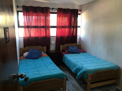 - 2 lits dans une petite chambre avec des rideaux rouges dans l'établissement Hostal Emporio, à Casablanca