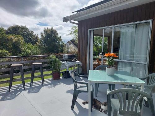 a patio with a table and chairs and a dog laying on it at Garden View on Hone Heke Kerikeri in Kerikeri