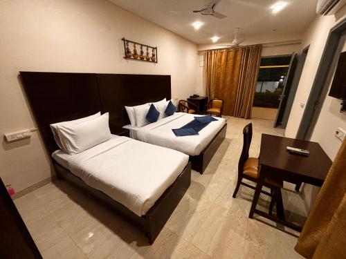 Cette chambre comprend deux lits et un bureau. dans l'établissement Atulya Green By Meyatri, à Jaipur