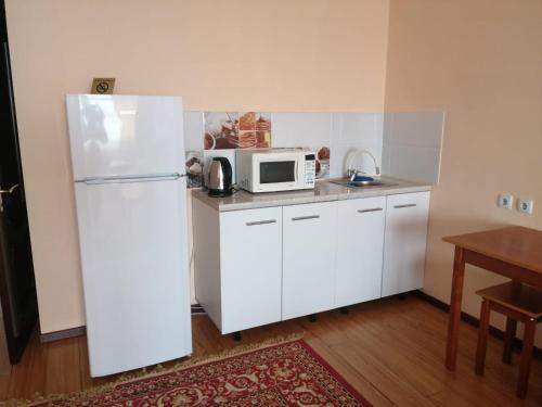 W kuchni znajduje się biała lodówka i kuchenka mikrofalowa. w obiekcie Северное Сияние 41 этаж 01 w mieście Astana