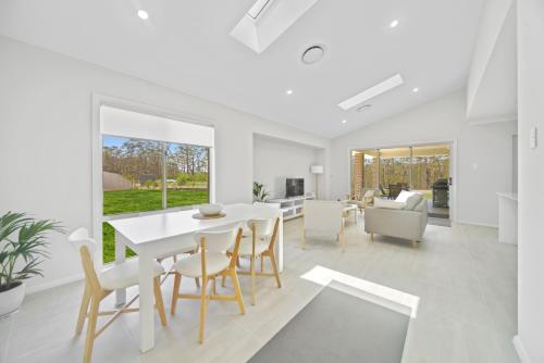 a dining room and living room with a white table and chairs at Fairway to Heaven in Sussex inlet