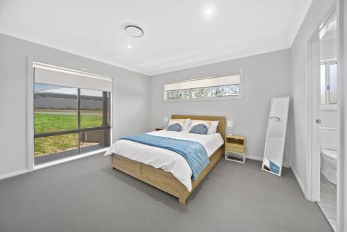 Una habitación blanca con una cama y una ventana en Fairway to Heaven, en Sussex Inlet