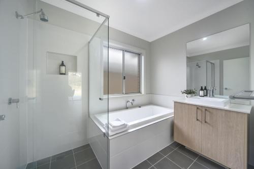 Un baño blanco con bañera y lavabo. en Fairway to Heaven, en Sussex Inlet