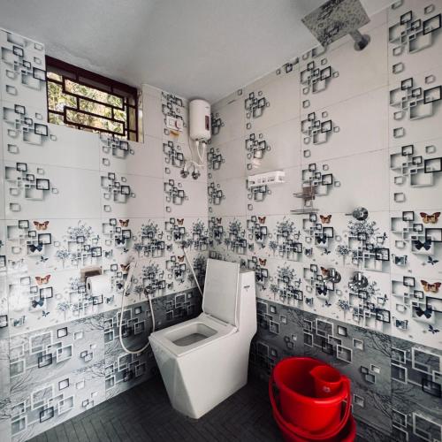 baño con aseo y pared cubierta de fotos en Wild Village Stay Gokarna en Gokarna