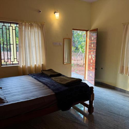 1 dormitorio con cama y ventana grande en Wild Village Stay Gokarna en Gokarna
