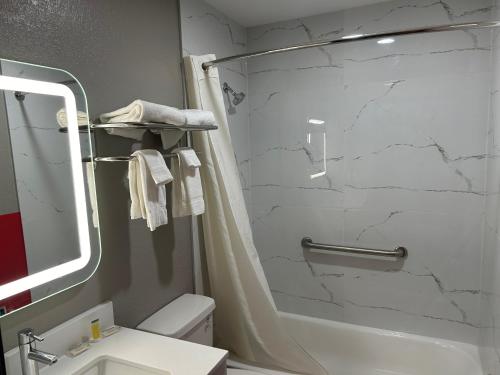 y baño con ducha, aseo y lavamanos. en Super 8 by Wyndham Lewiston Auburn Area en Lewiston