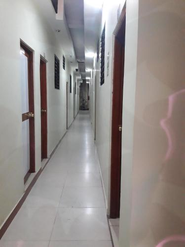 un pasillo vacío con paredes blancas y un pasillo largo en Hostal Real Center en Iquitos