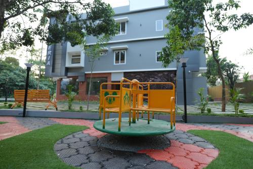 a playground in a park in front of a building at Mesteria Inn Wayanad in Wayanad