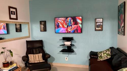 uma sala de estar com uma cadeira e uma televisão na parede em House TT do Vidigal no Rio de Janeiro