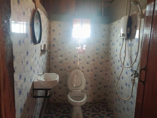 a bathroom with a toilet and a sink and a light at Banlung Hill Top House &Trekking in Phumĭ Pôy