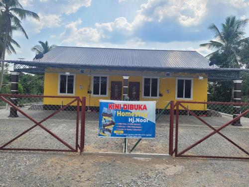 a yellow house with a sign in front of it at Homestay Haji Noor in Tanah Merah