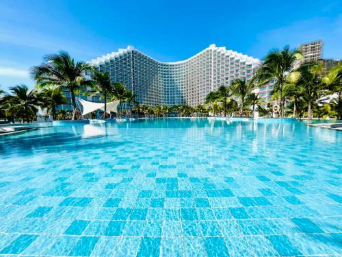 a large swimming pool with a resort in the background at Cam Ranh provided by Pearl in Miếu Ông