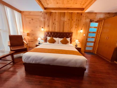 Vista Resort, Manali - centrally Heated & Air cooled luxury rooms في مانالي: غرفة نوم بسرير كبير وكرسي