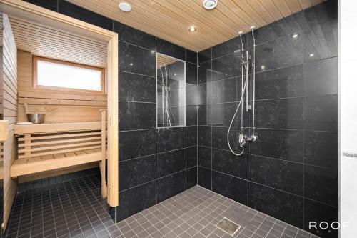a bathroom with a shower with black tiles at Cozy Holiday Home with Outside Jacuzzi in Espoo