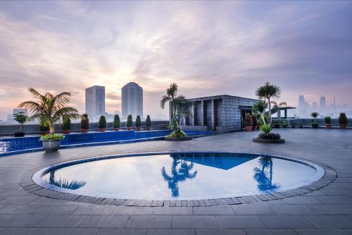a pool on the roof of a building with a city skyline at Merlynn Park Hotel in Jakarta
