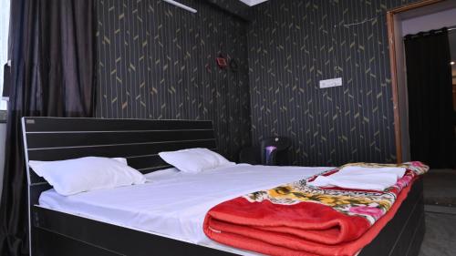 a bed with white sheets and a red blanket on it at Great escape in Lucknow