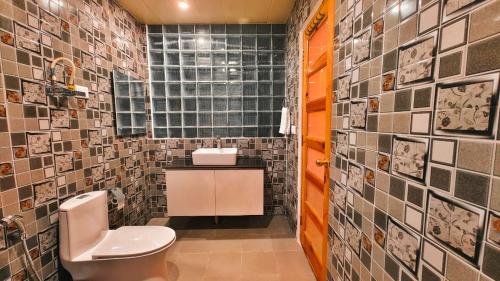 a bathroom with a toilet and a tile wall at Vista Resort, Manali - centrally Heated & Air cooled luxury rooms in Manāli