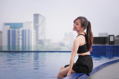 a woman sitting on the edge of a swimming pool at Merlynn Park Hotel in Jakarta