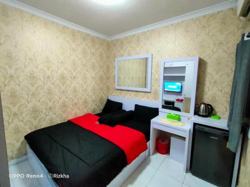 a bedroom with a bed and a desk with a computer at Zye Rooms apartemen in Teko