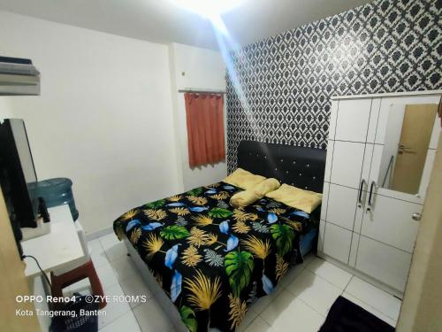 a bedroom with a bed with a black and blue comforter at Zye Rooms apartemen in Teko