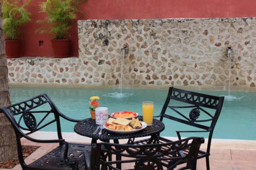 a table with a plate of food next to a pool at Casa Vicenta Izamal in Izamal