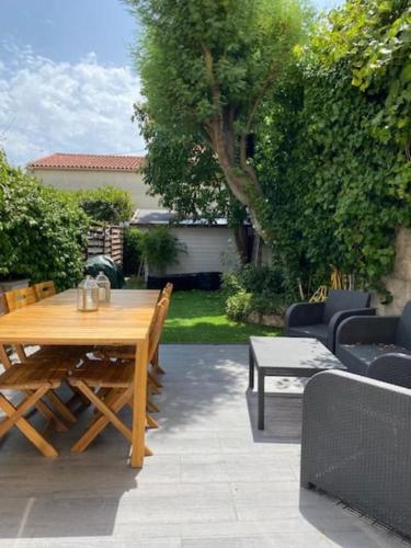 - une table et des chaises en bois dans une arrière-cour avec une table et des chaises dans l'établissement BEAU REZ DE JARDIN- Cannes Suquet - Clim- Calme - Lumineux- 15 minutes Palais des Festival, à Cannes