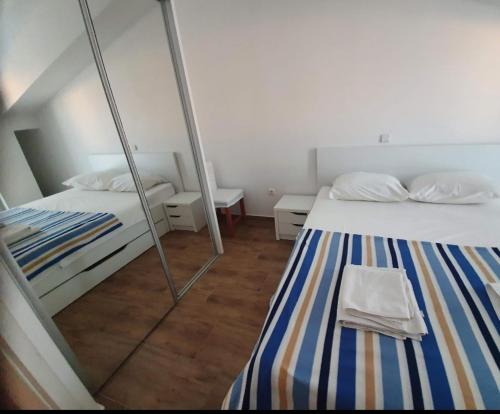 two beds in a room with a mirror at AtlantisPagNovalja in Zubovići