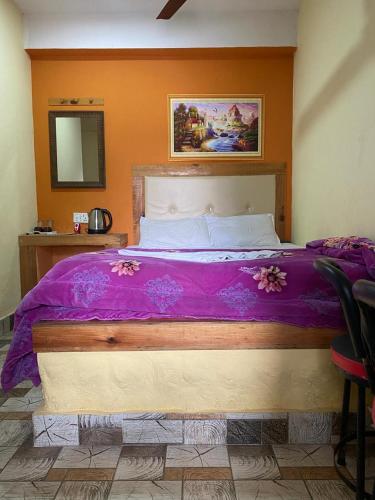 a bedroom with a large bed with purple sheets at Hong Qi Hotel in Chitwan