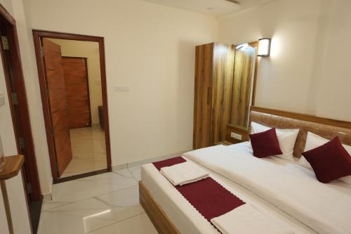 a bedroom with a large white bed with red pillows at Mesteria Inn Wayanad in Wayanad