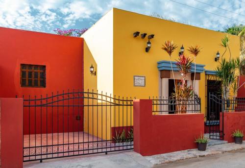 a yellow and red house with a red fence at Casa Vicenta Izamal in Izamal