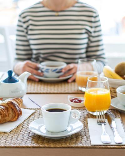 a person sitting at a table with coffee and orange juice at Hôtel De La Plage in Courseulles-sur-Mer