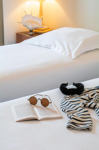 a bed with a book and glasses and a towel at Hôtel De La Plage in Courseulles-sur-Mer
