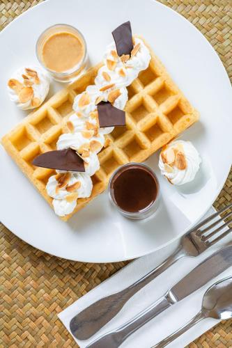 a white plate with a waffle with whipped cream and syrup at Hôtel De La Plage in Courseulles-sur-Mer
