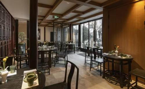 a restaurant with tables and chairs in a room at Yihe Riverside Suzhou in Suzhou