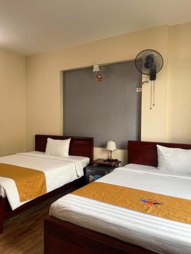 a hotel room with two beds and a fan at Khách sạn HOÀ BÌNH QUẢNG TRỊ in Ðông Hà