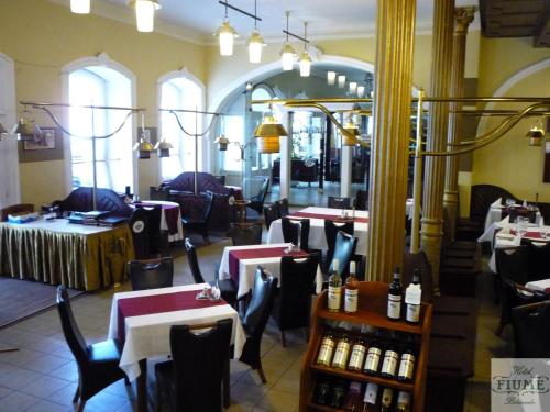 a restaurant with tables and chairs and bottles of wine at Fiume Hotel in Békéscsaba
