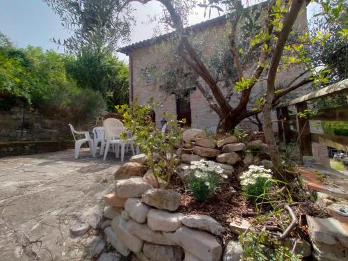 a garden with a stone wall and a tree at Maison en Pierre in Fiastra
