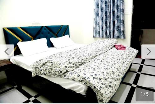 a bed with a black and white comforter and pillows at Jolly Hill Stay in Doiwāla