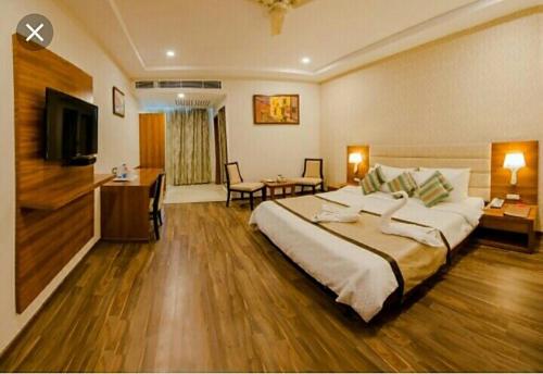 ein Hotelzimmer mit einem großen Bett und einem Schreibtisch in der Unterkunft Hotel New Ashiyana Palace Varanasi - Fully-Air-Conditioned hotel at prime location With Wifi , Near-Kashi-Vishwanath-Temple, and-Ganga-ghat - Best Hotel in Varanasi in Varanasi