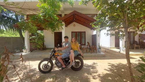 a man and woman sitting on a motorcycle in front of a house at The Dream Inn Guesthouse Passikudah in Batticaloa