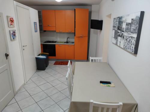 uma cozinha com armários laranja e uma mesa e cadeiras brancas em Cortile Maggiore Home em Cefalù