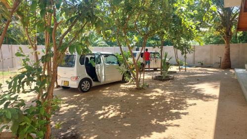 a small white car parked under some trees at The Dream Inn Guesthouse Passikudah in Batticaloa