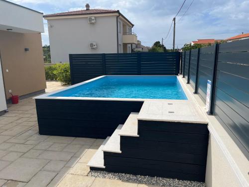 a swimming pool on a house with a black fence at Poolhouse Flip Flop - mit privatem Pool in Vir