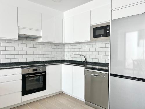 una cucina bianca con lavandino e lavastoviglie di Moderno apartamento con gran terraza a Roses
