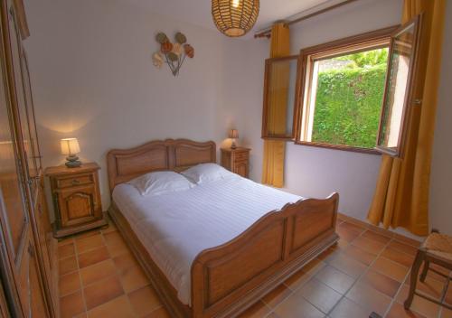 a bedroom with a wooden bed and a window at Villa Ma Rosa, 160m2, 4ch, Piscine et Jardin in Mandelieu-la-Napoule