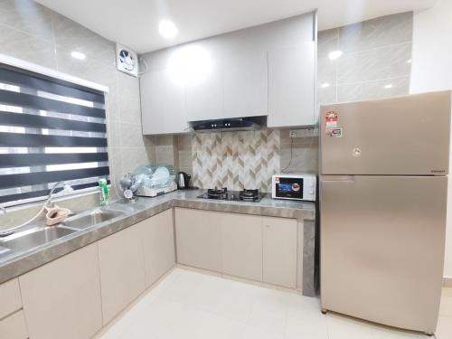 a kitchen with white cabinets and a refrigerator at 232 Permai Duyung Family Gathering in Seremban