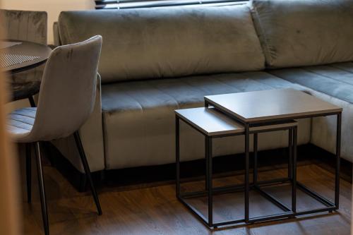 a couch with two tables and a chair in a room at Apartament Prestige in Nowy Sącz