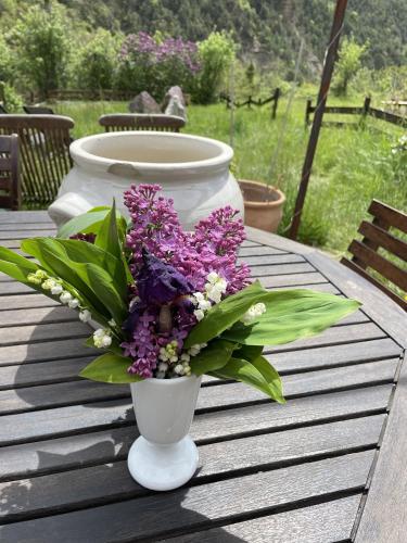 a white vase with purple flowers on a table at Maison Gaia in Valdeblore