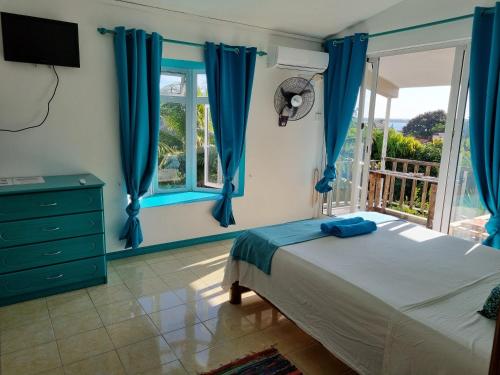 1 dormitorio con cortinas azules, 1 cama y ventana en Surf House, en La Gaulette